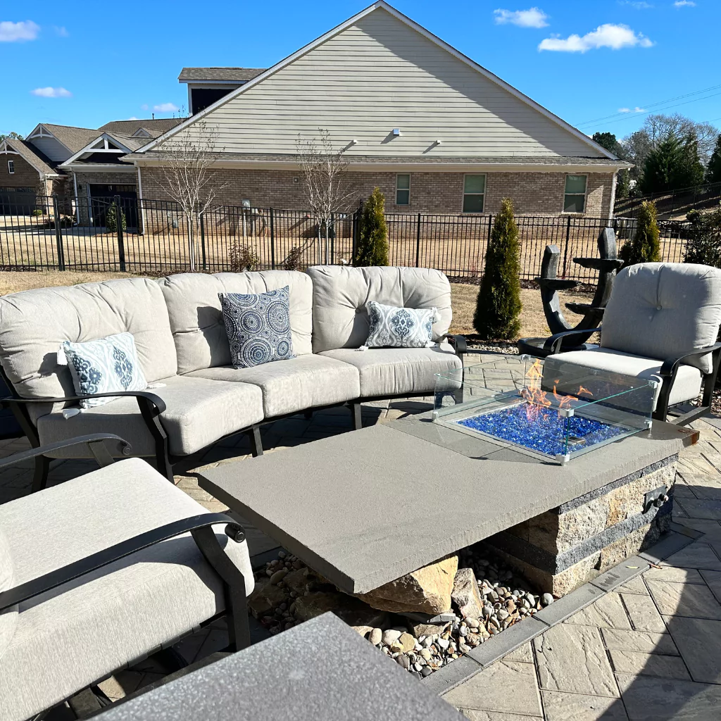 A fire pit surrounded by outdoor furniture with cushions in them