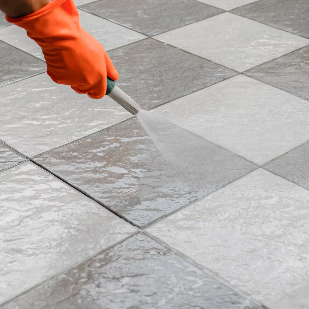 A person cleaning with water a stone floor as part of a first step maintenance