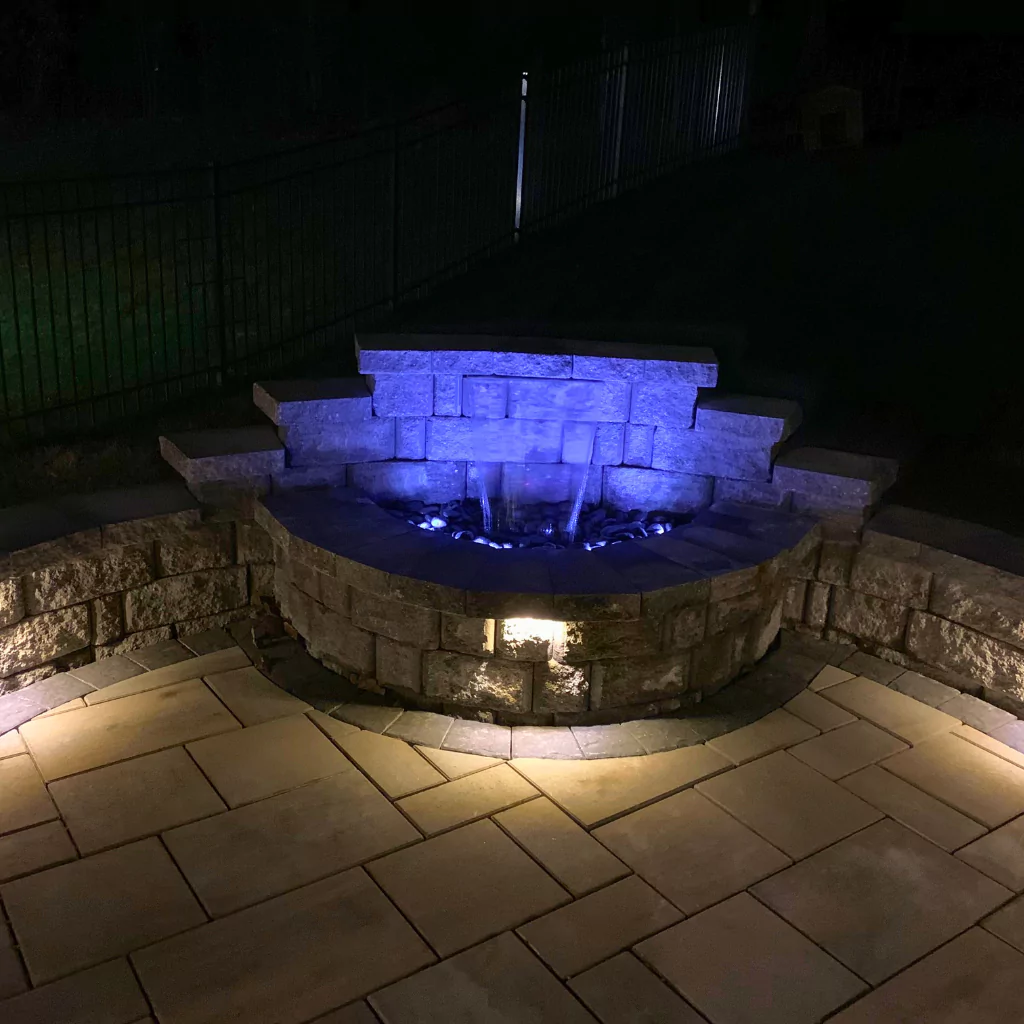 A fountain with color-changing LED lights that illuminate the space at night.
