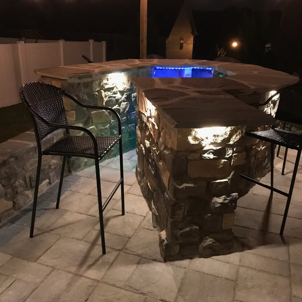 A stone outdoor kitchen with built-in lighting