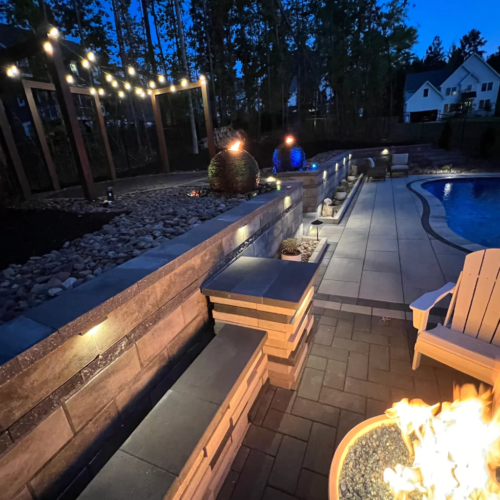 A beautiful patio with a swimming pool, a fire pit and various light effects that create a magical atmosphere at night.