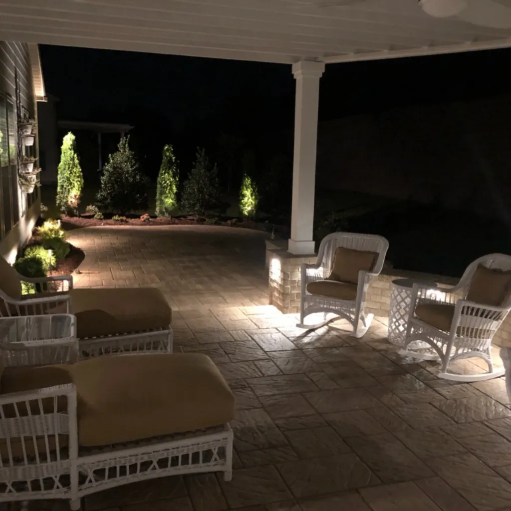 A roofed patio with lighting near the ground. It creates a cozy effect together with the furniture seen in the photo.