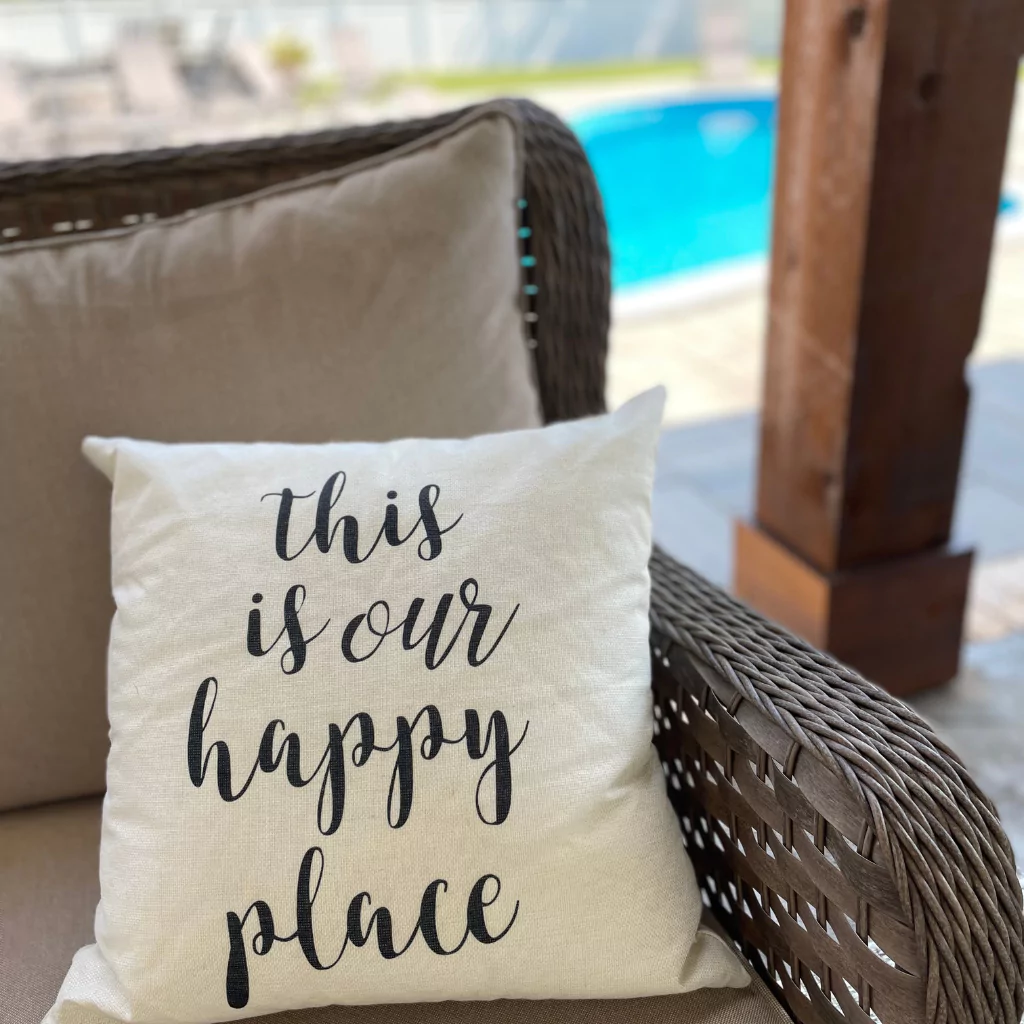 A cushion on a patio sofa that says "Your happy place".
