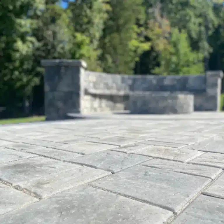 A beautiful and well done stone paver with a stone sitting wall and stone firepit at the botom of the photo.