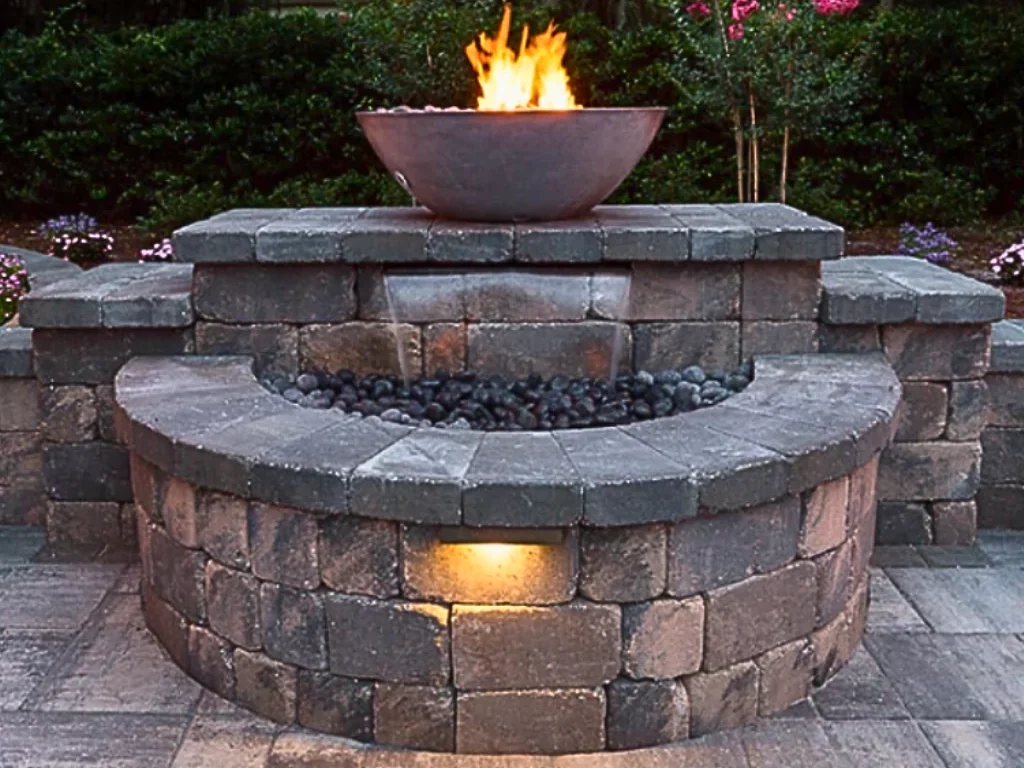 A beautiful stone fountain built in a courtyard. It has fire features that complement the design and makes a unique blend of the elements stone, water and fire.
