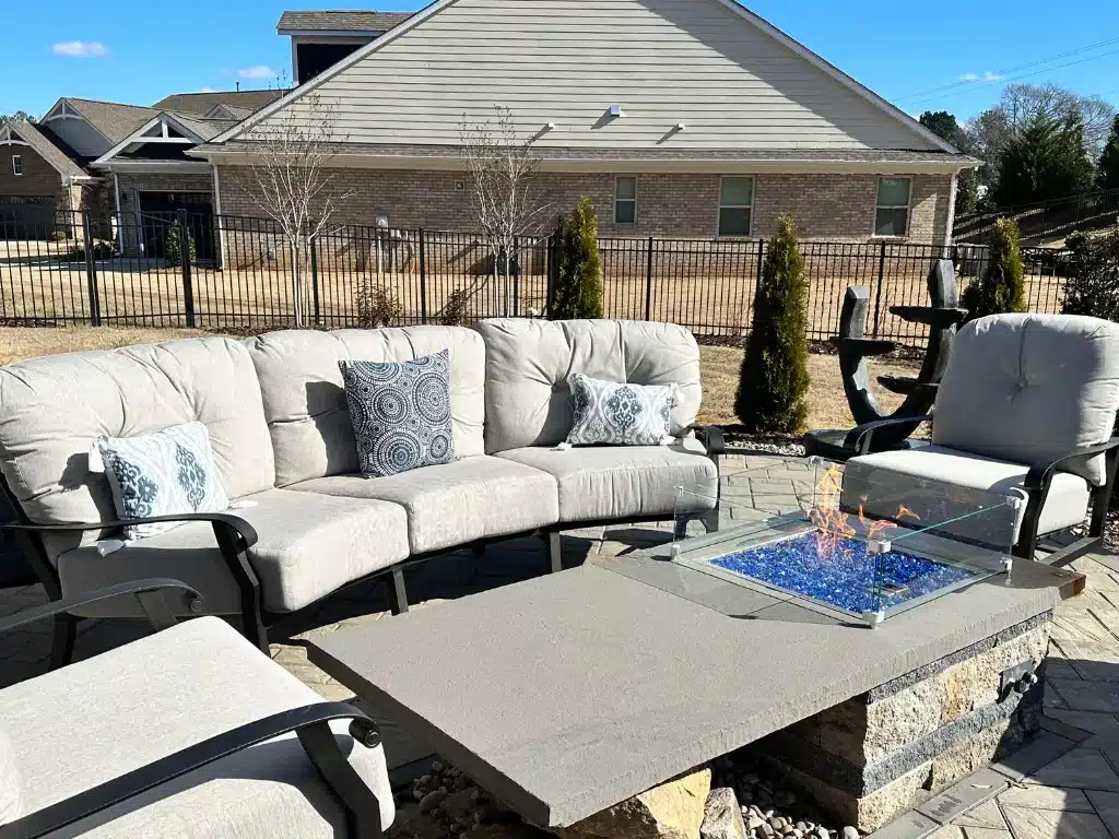 A fire pit surrounded by outdoor furniture with cushions in them