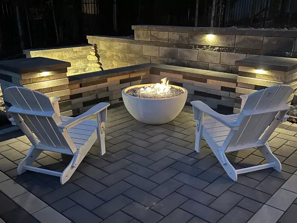 A cozy firepit at night with chairs around it.