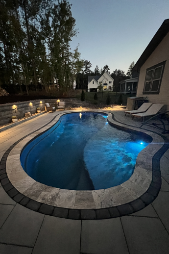 A beautiful swimming pool in a patio. It is at night and the illumination of the pool creates a spectacular effect.