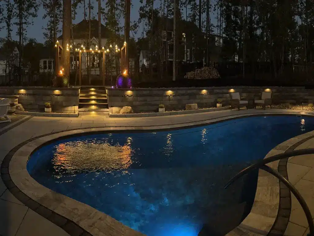 SunSouth Carolinas creates luxurious poolside retreats featuring custom pool designs, extensive hardscaping, retaining walls, and layered landscape lighting.