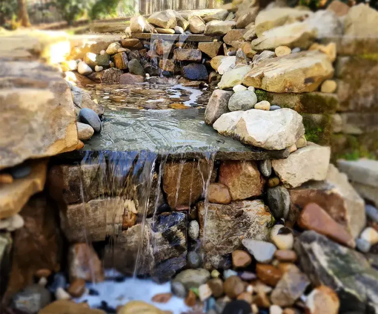 Outdoor Water Features 1 Natural rock waterfall installation by SunSouth Carolinas, featuring cascading water over carefully placed boulders for an organic backyard water feature.
