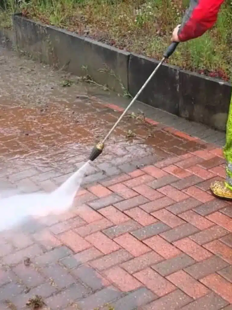 A person cleaning a paver with specialized tools to prepare your patio for the changing season