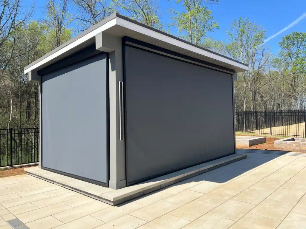 Modern freestanding outdoor structure with retractable screens designed by SunSouth Carolinas, offering versatile, enclosed shelter on a custom hardscaping patio.