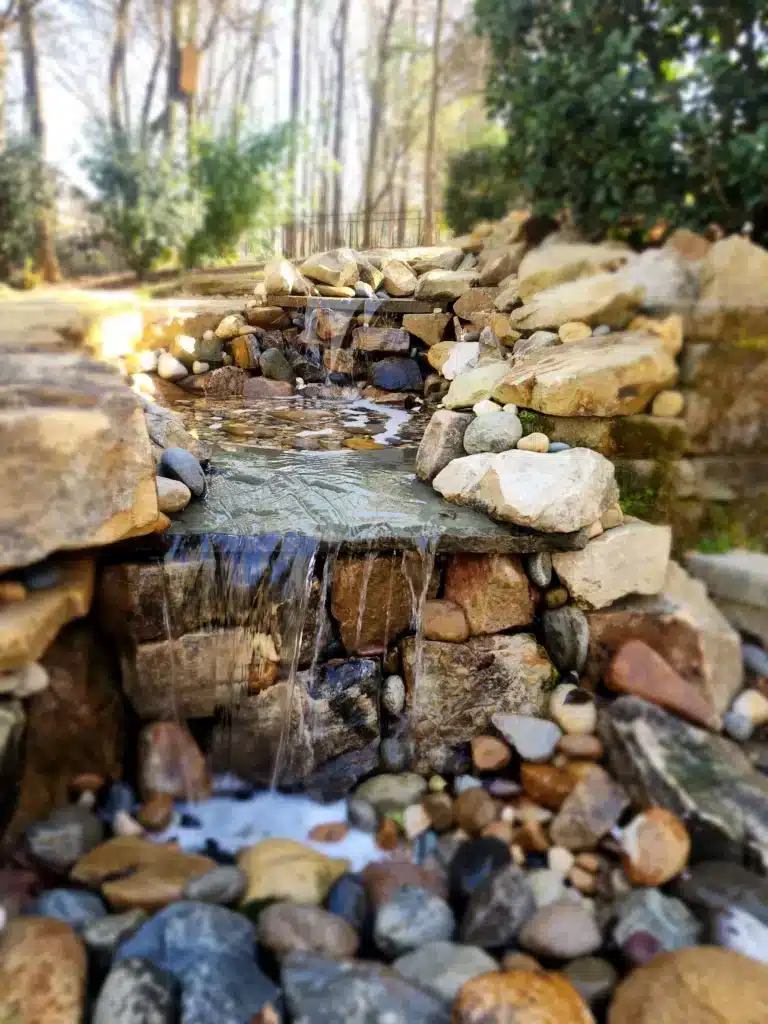 Expert construction of an outdoor water feature: SunSouth Carolinas uses hardscaping and masonry skills to create realistic rock waterfalls for landscaping.