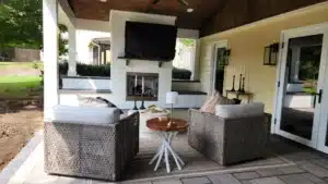 Enjoy year-round comfort in an outdoor living space by SunSouth Carolinas, complete with a built-in masonry outdoor fireplace, integrated lighting, and stylish hardscaping.