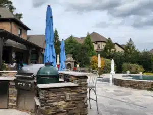 SunSouth Carolinas excels in custom outdoor kitchens, shown here with detailed stone masonry, integrated appliances, and situated on extensive pool deck hardscaping.