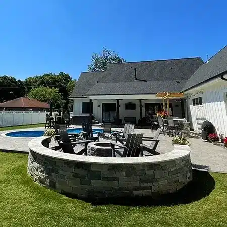 Custom stone fire pit built by SunSouth Carolinas, featuring a circular design and ample seating, perfect for outdoor gatherings. Includes hardscaping and landscaping. Late summer landscaping.
