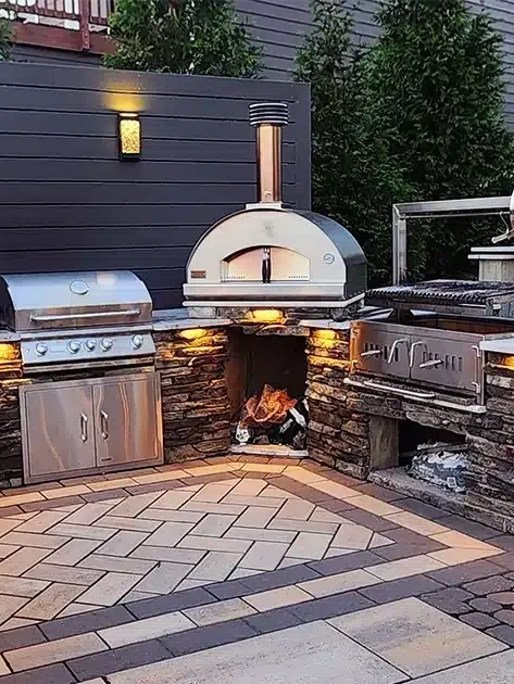 Charlotte Backyard Trends: What Homeowners Are Planning Before Spring 4 Luxury hardscaping project includes this stunning custom outdoor kitchen installation by SunSouth Carolinas, showcasing beautiful stone masonry, specialty pizza oven, and accent custom outdoor lighting.