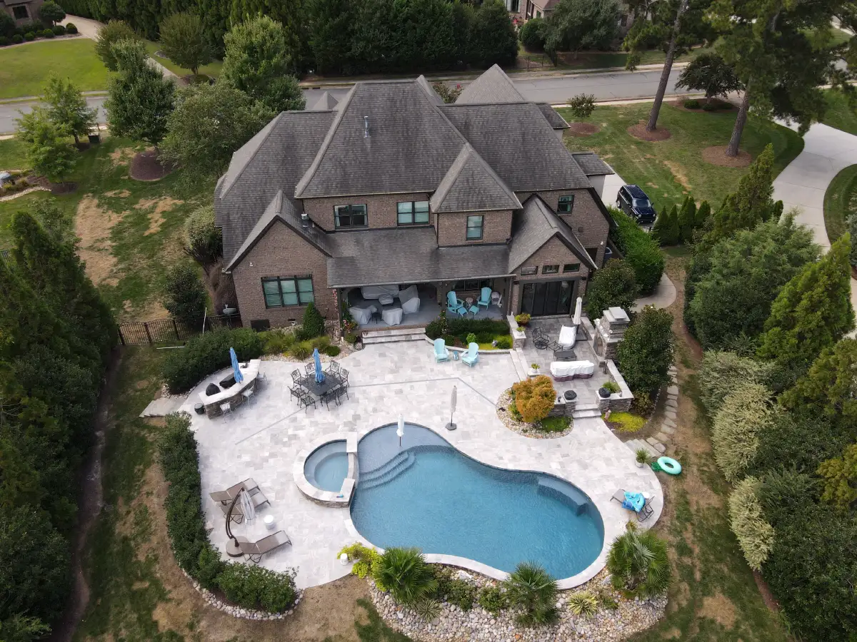 Why Winter Is the Smartest Time to Design Your Backyard in Raleigh 1 A breathtaking aerial view of the ultimate backyard resort, featuring a custom freeform pool, spa, and sprawling paver patio designed and built by SunSouth Carolinas.