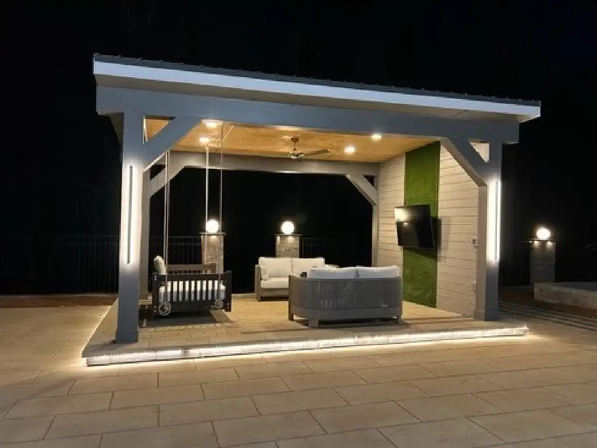 A modern patio pavilion at night, featuring a sophisticated lighting design with integrated LEDs on the posts, under the floor, and in the ceiling by SunSouth Carolinas.